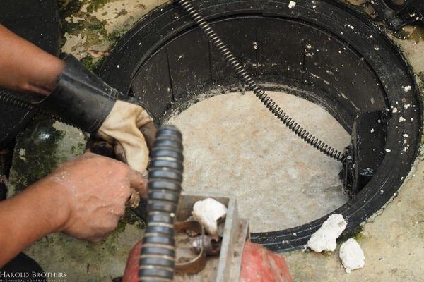 A person using an auger on a clog